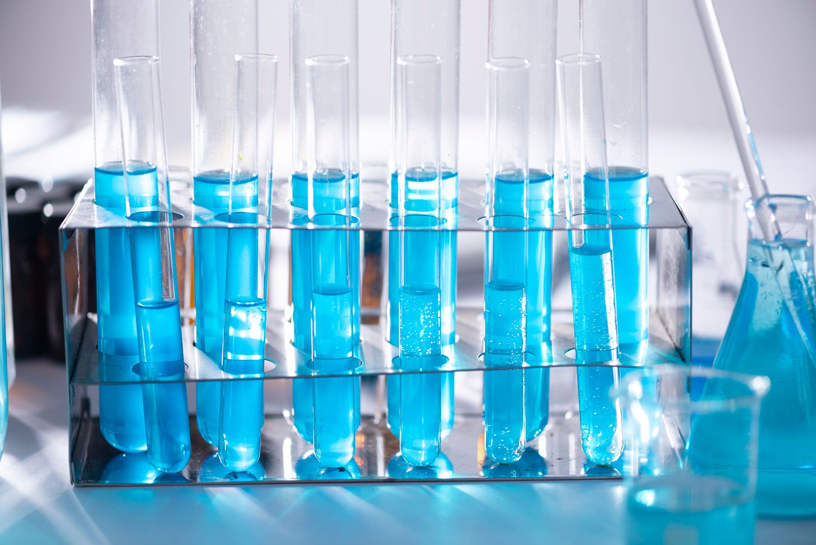 Laboratory glassware with blue solutions on a bench, standing in for materials chemistry and fiber spinning research. Photo: Pexels.