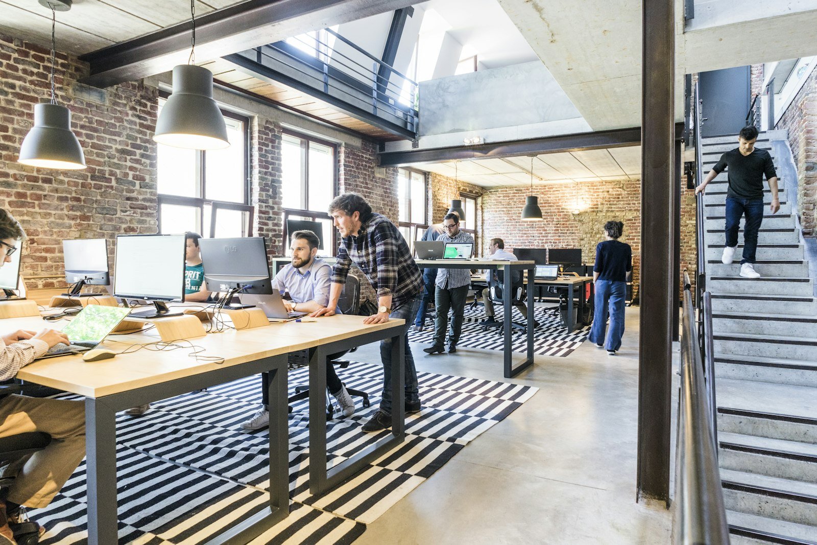 Colleagues collaborating around laptops in an open office—process and architecture decisions still need a shared canvas. Photo: Proxyclick / Unsplash.