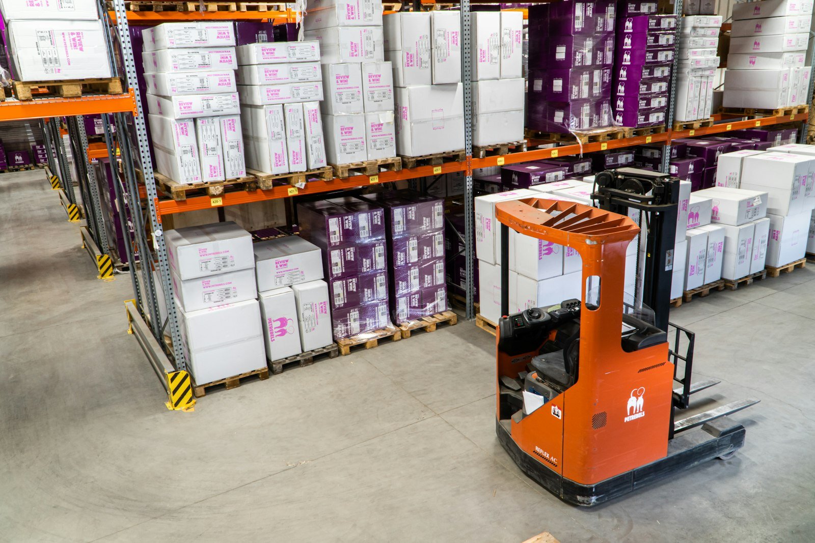 Industrial warehouse aisle with reach forklift and racked inventory—the governed ops layer agents must respect. Photo: Unsplash.