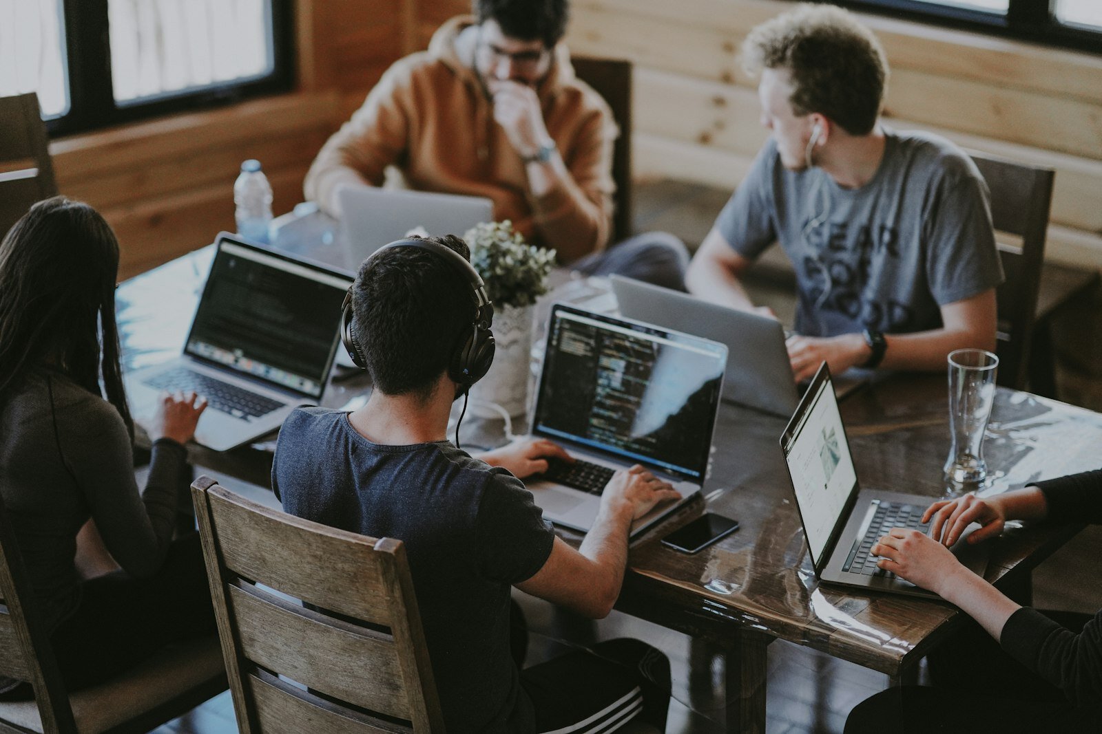 Team collaborating around a table with laptops—transformation sticks when people and agents share the same process model. Photo: Annie Spratt / Unsplash.