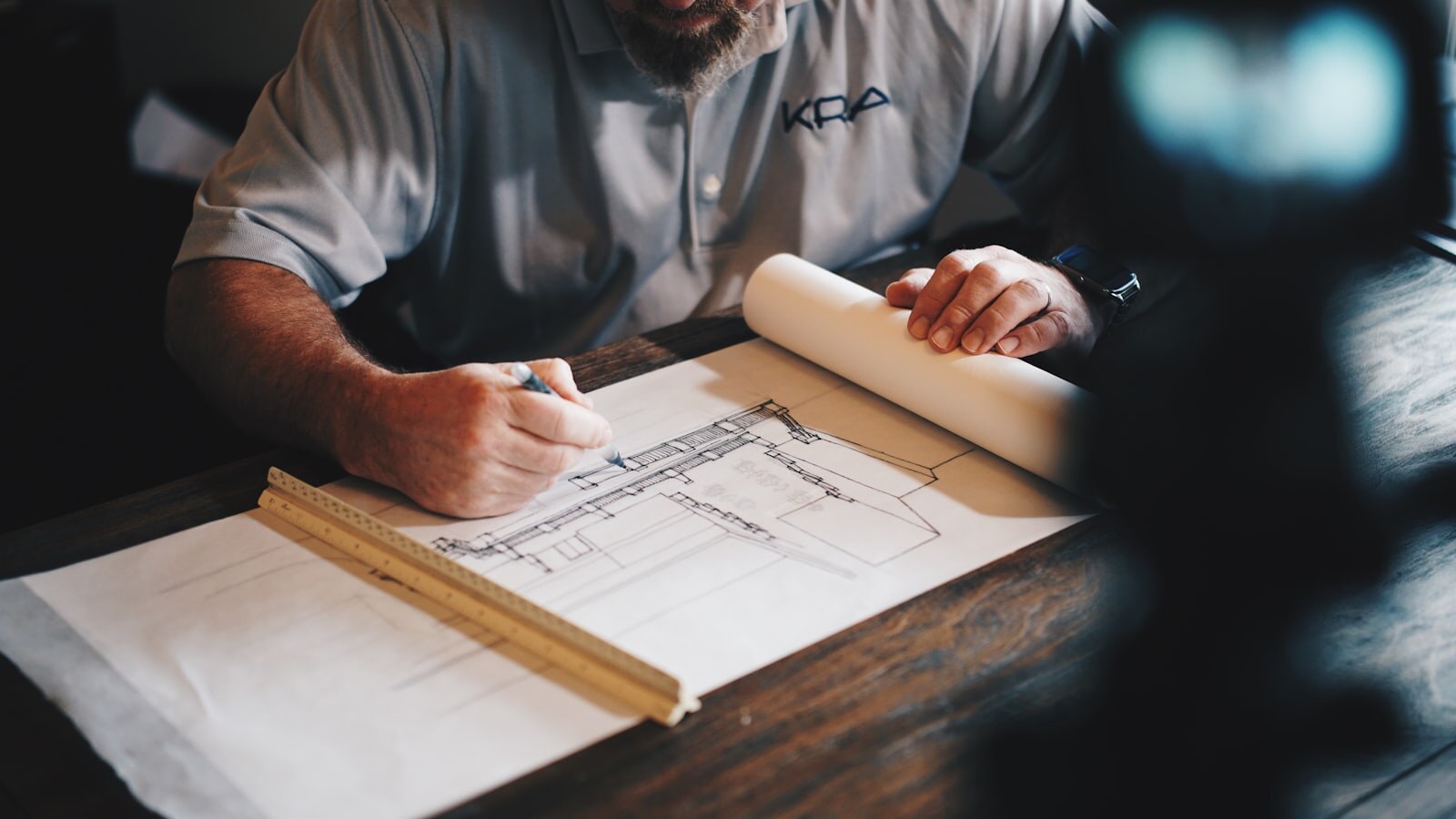Engineer drafting a technical section drawing with a scale ruler on a wooden desk. Photo: Unsplash.