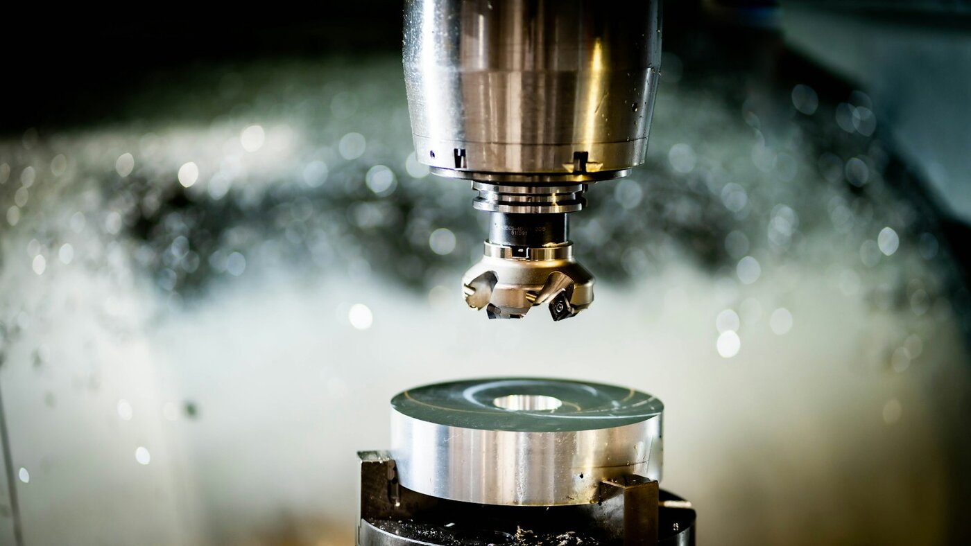 CNC machine cutting metal on the shop floor—where fixture-aware pocketing and smoother posted motion have to survive real spindles. Photo: Unsplash.