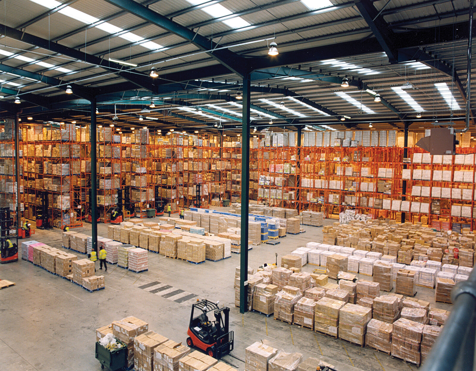 Modern warehouse with pallet-rack storage—aftermarket parts and logistics context for industrial CRM. Photo: Wikimedia Commons.