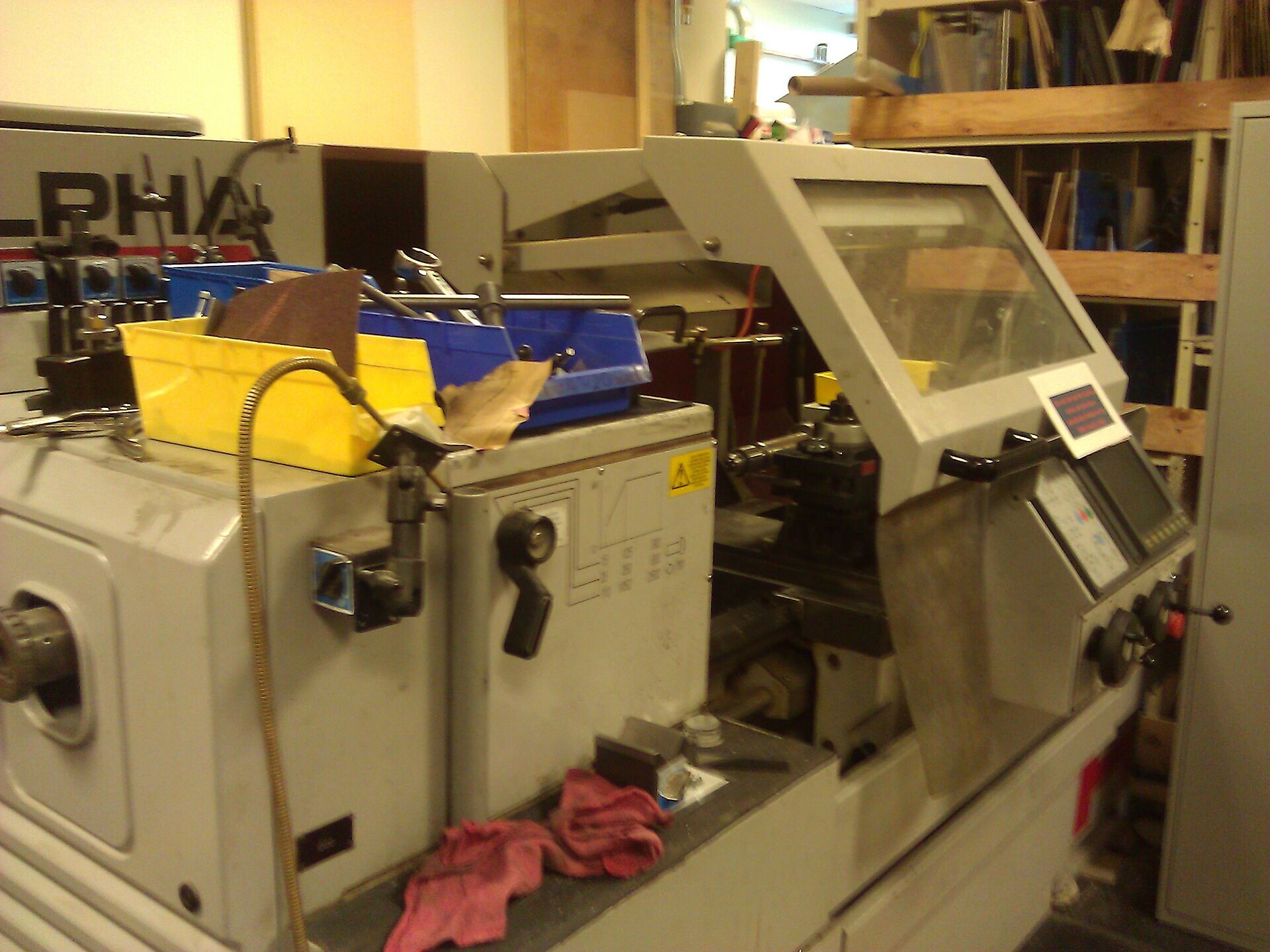 ALPHA CNC lathe with tools and shop rags—lived-in machining cell where schedule intelligence and OEE must match what the spindle is doing now. Photo: Wikimedia Commons.