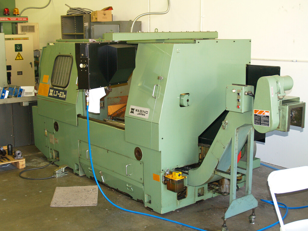 WASINO CNC lathe on a shop floor—the kind of discrete machining cell MaximaOS connects for reactive work-order and downtime truth. Photo: Wikimedia Commons.