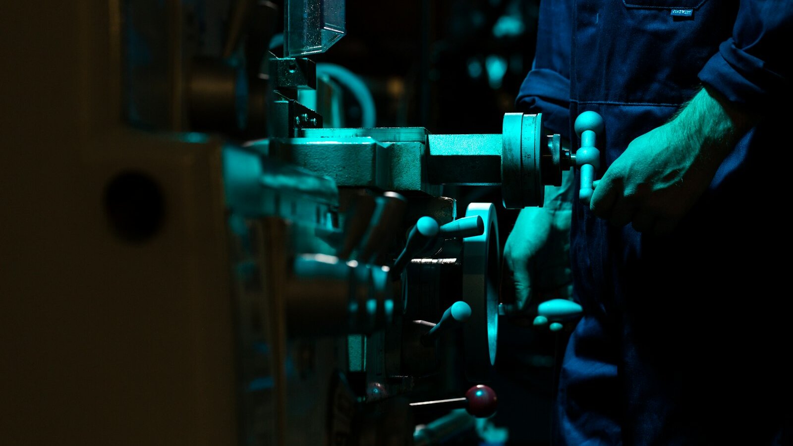Technician adjusting precision equipment on a factory production line