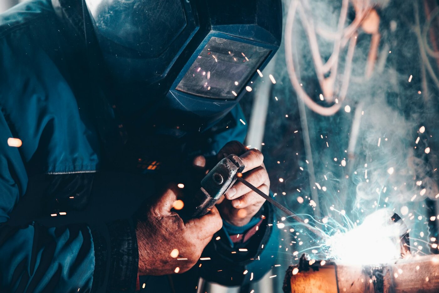 Welder joining metal with sparks in a manufacturing shop