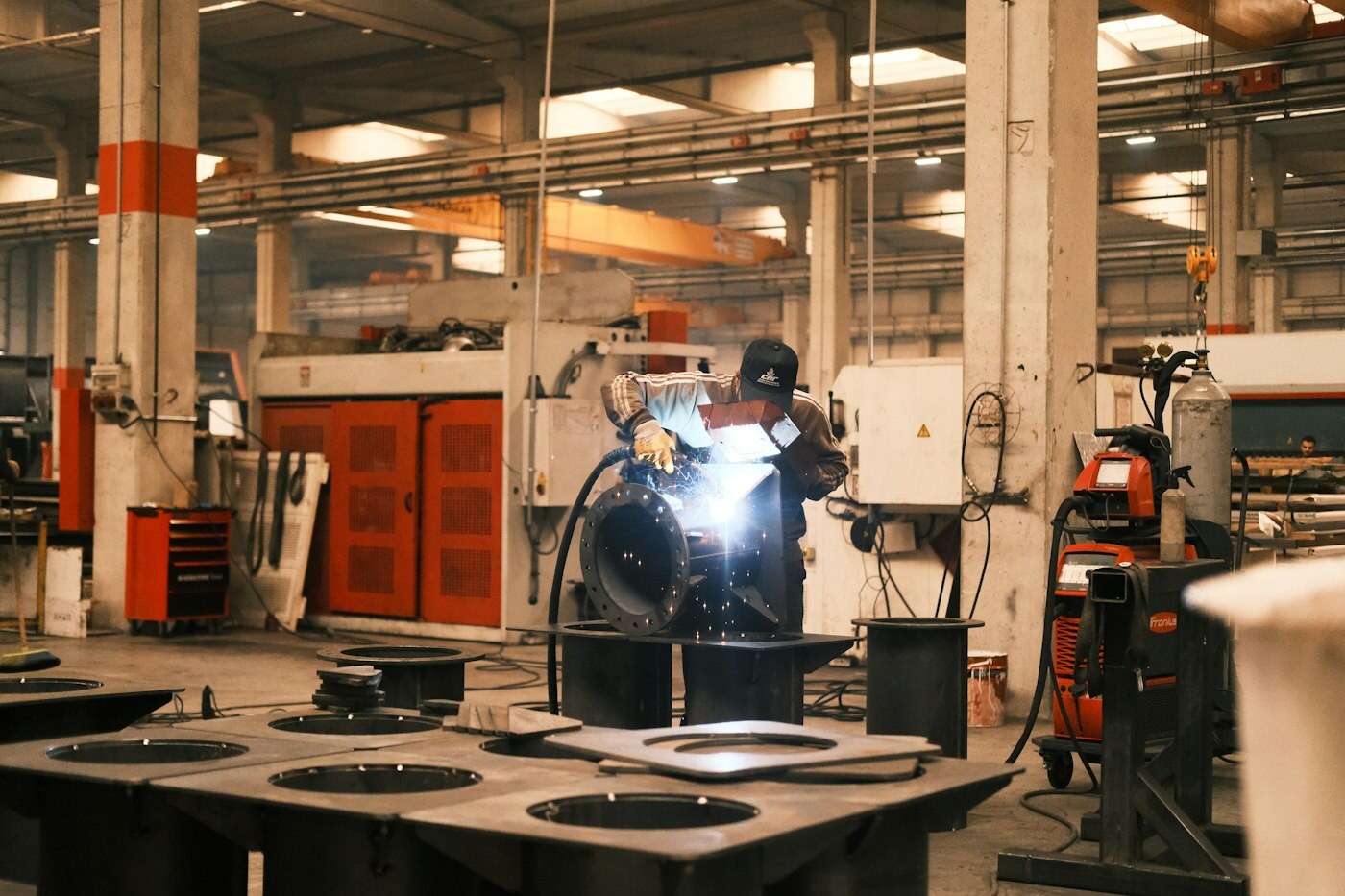 Factory worker welding metal on a shop floor—manufacturing reuse of engineered product structures. Photo: Unsplash.