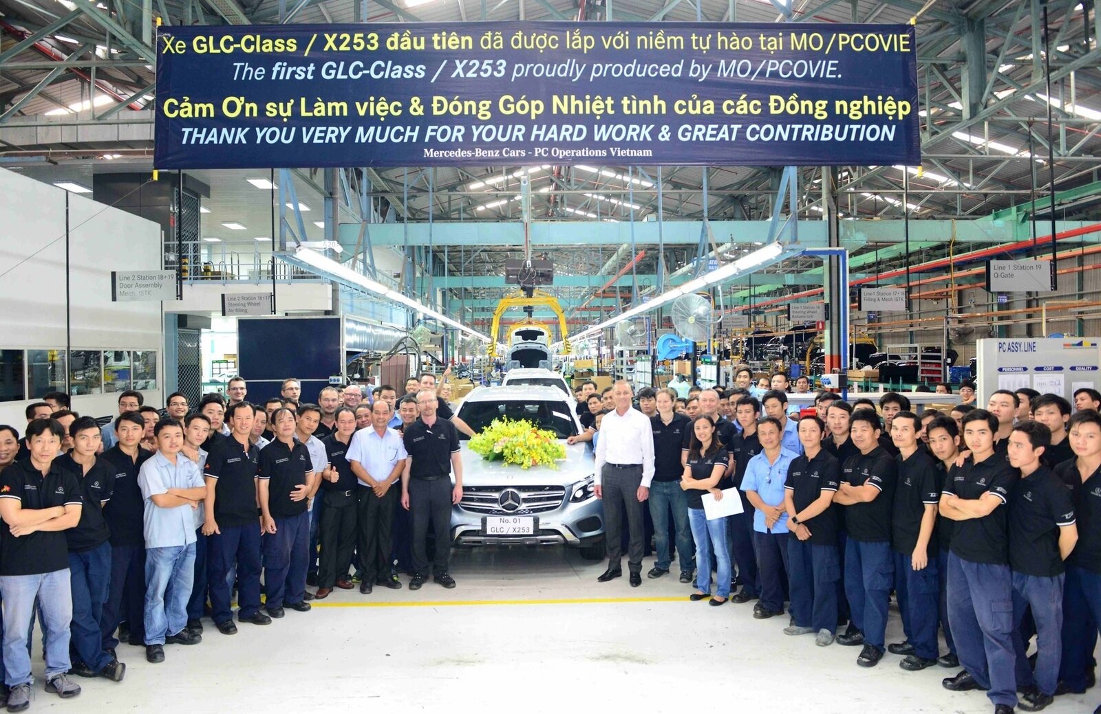 Automotive plant team on the factory floor celebrating first unit assembly—multi-site programs need one audit-ready gate truth. Photo: Wikimedia Commons.
