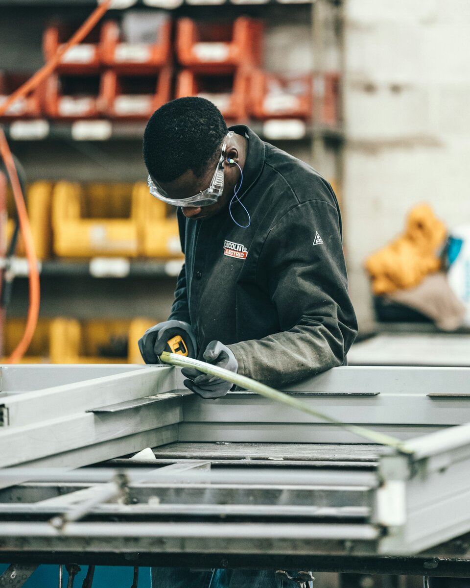 Engineer measuring a metal frame in a workshop—precision geometry and PMI that must stay attached to the part. Photo: Unsplash.