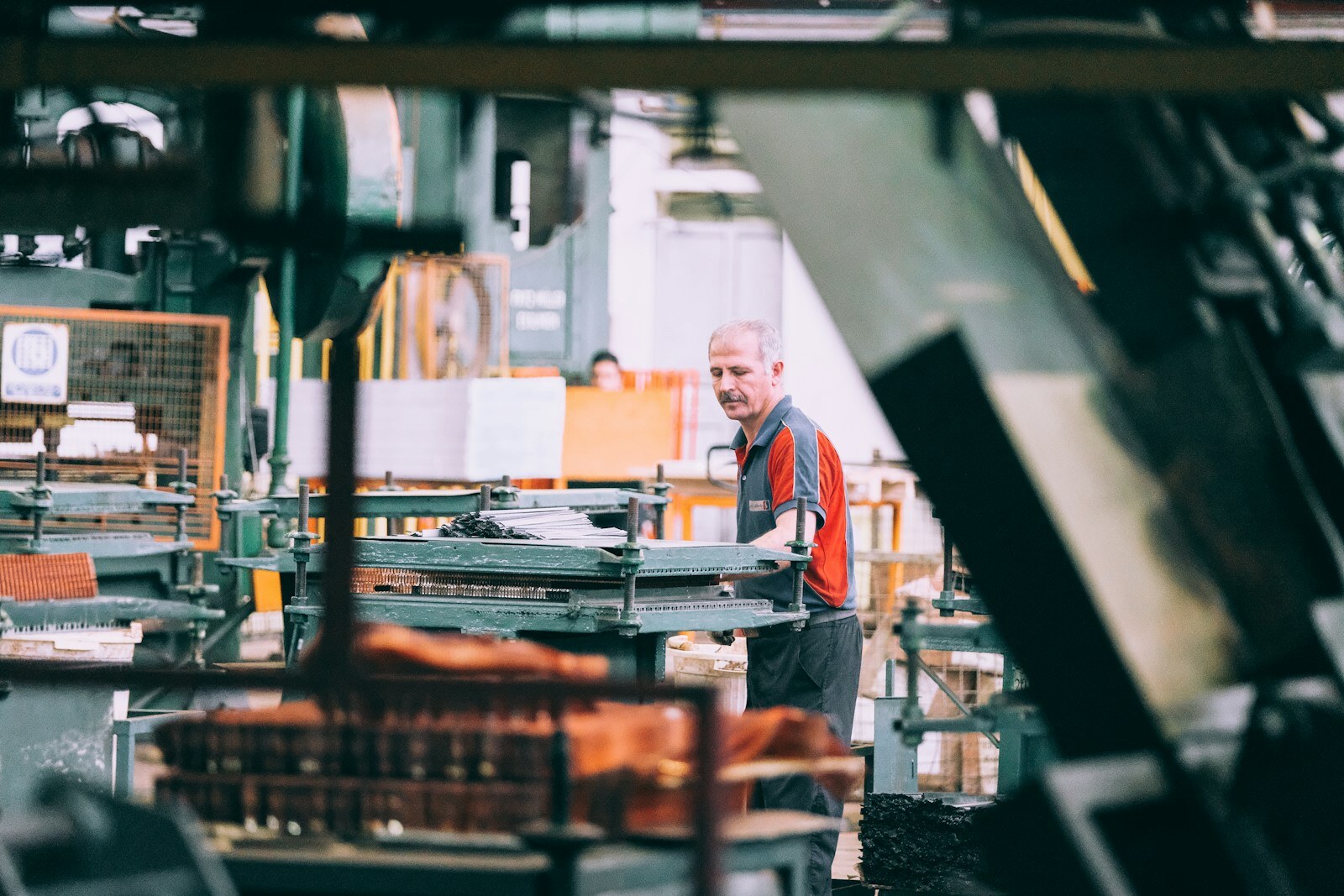 Factory technician in a grey shirt operating industrial machinery on the plant floor