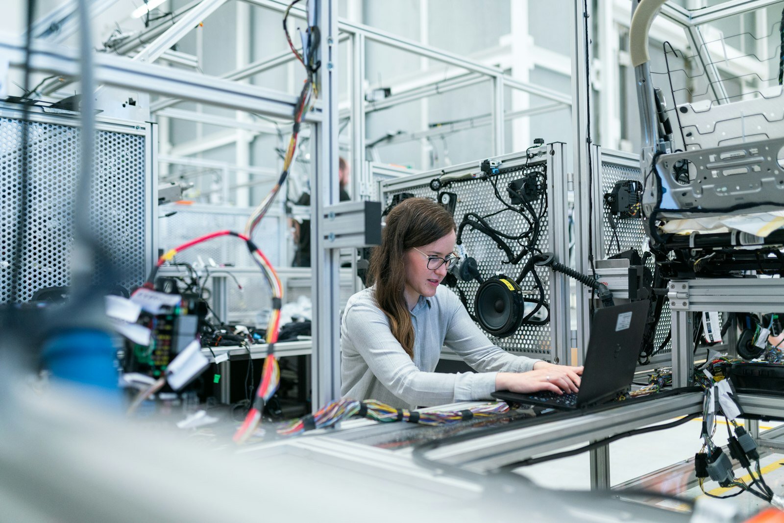 Engineer at a laptop in an industrial lab with aluminum framing and wiring harnesses