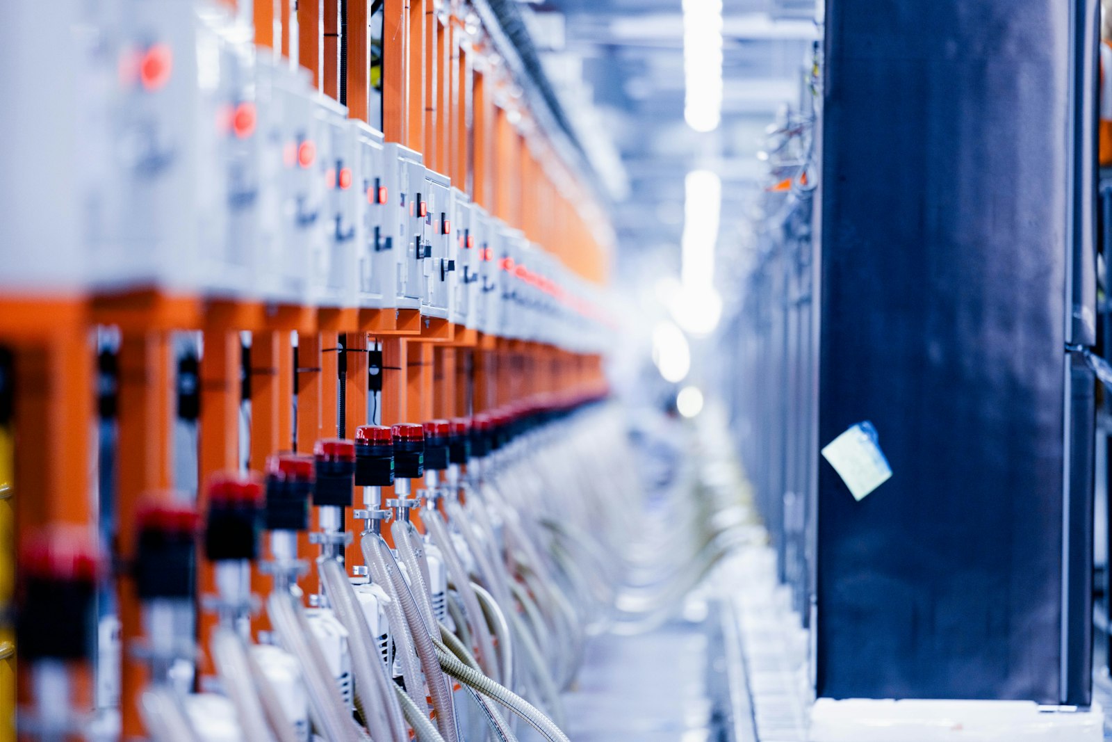 Row of orange-framed industrial process equipment along a factory corridor