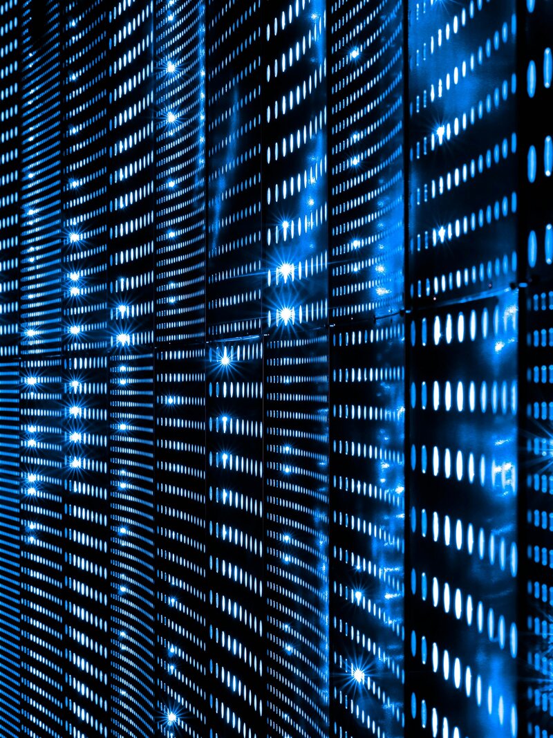 Tall server racks lit with blue indicator lights in a dark data hall