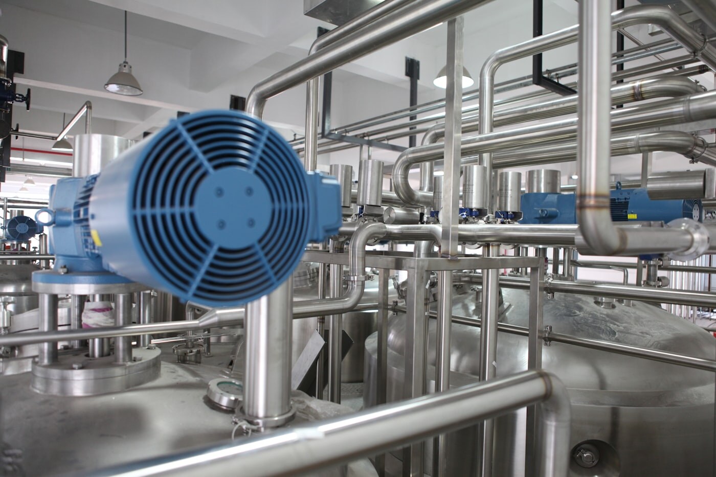 Stainless steel process plant with blue motors and dense piping. Photo: Unsplash.