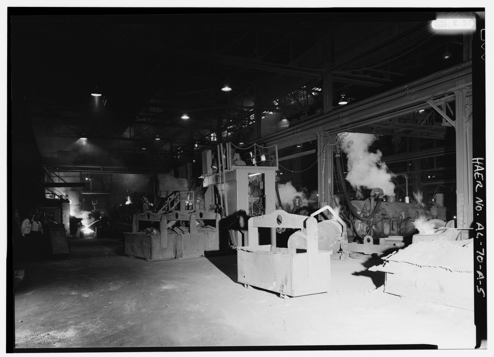 Molten iron poured from a cupola into a transfer ladle beside a casting machine