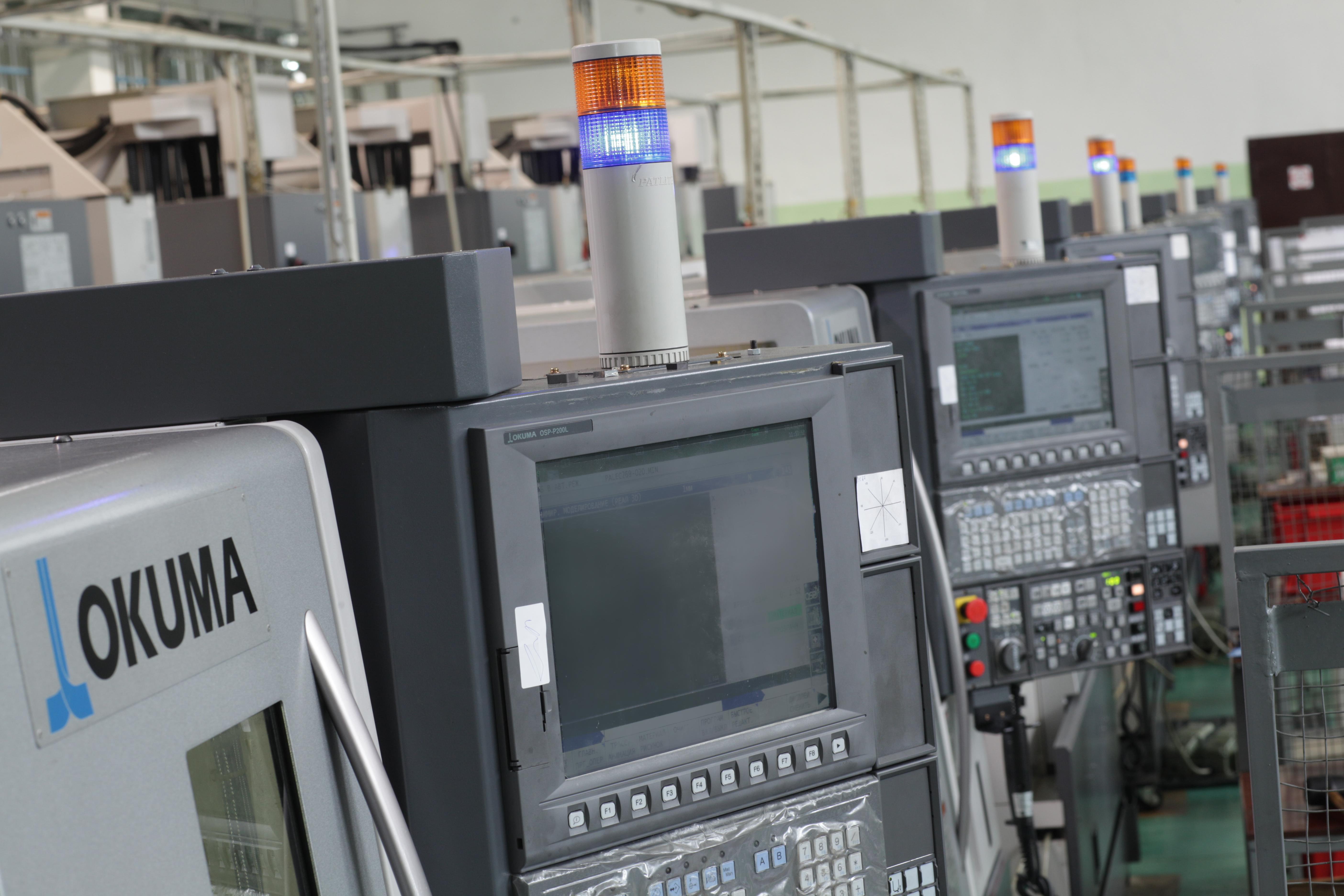Row of Okuma CNC lathes with stack lights at the Fenox automotive brake-parts plant.