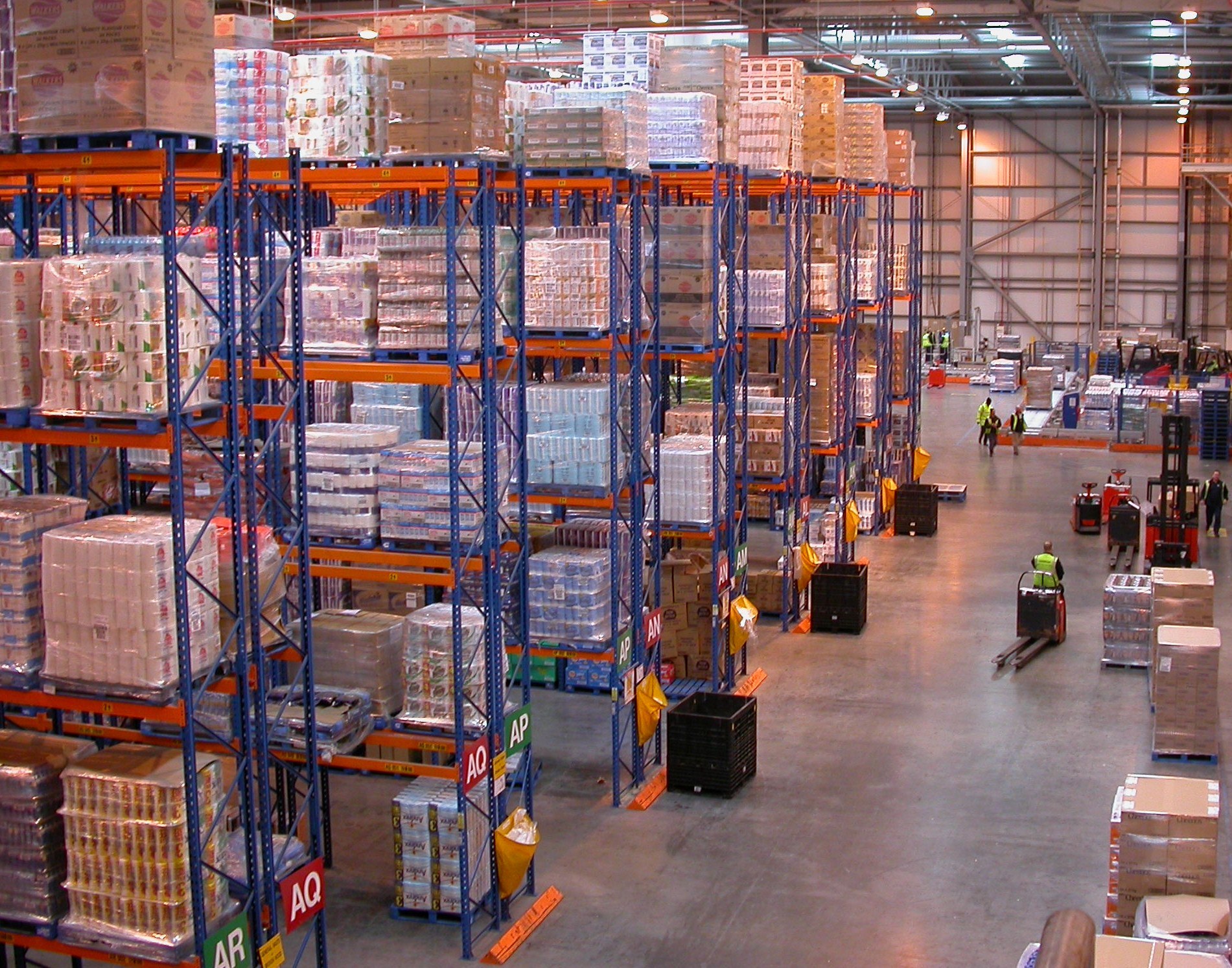 Tall orange and blue pallet racks loaded with goods inside a Sainsbury's regional distribution centre.