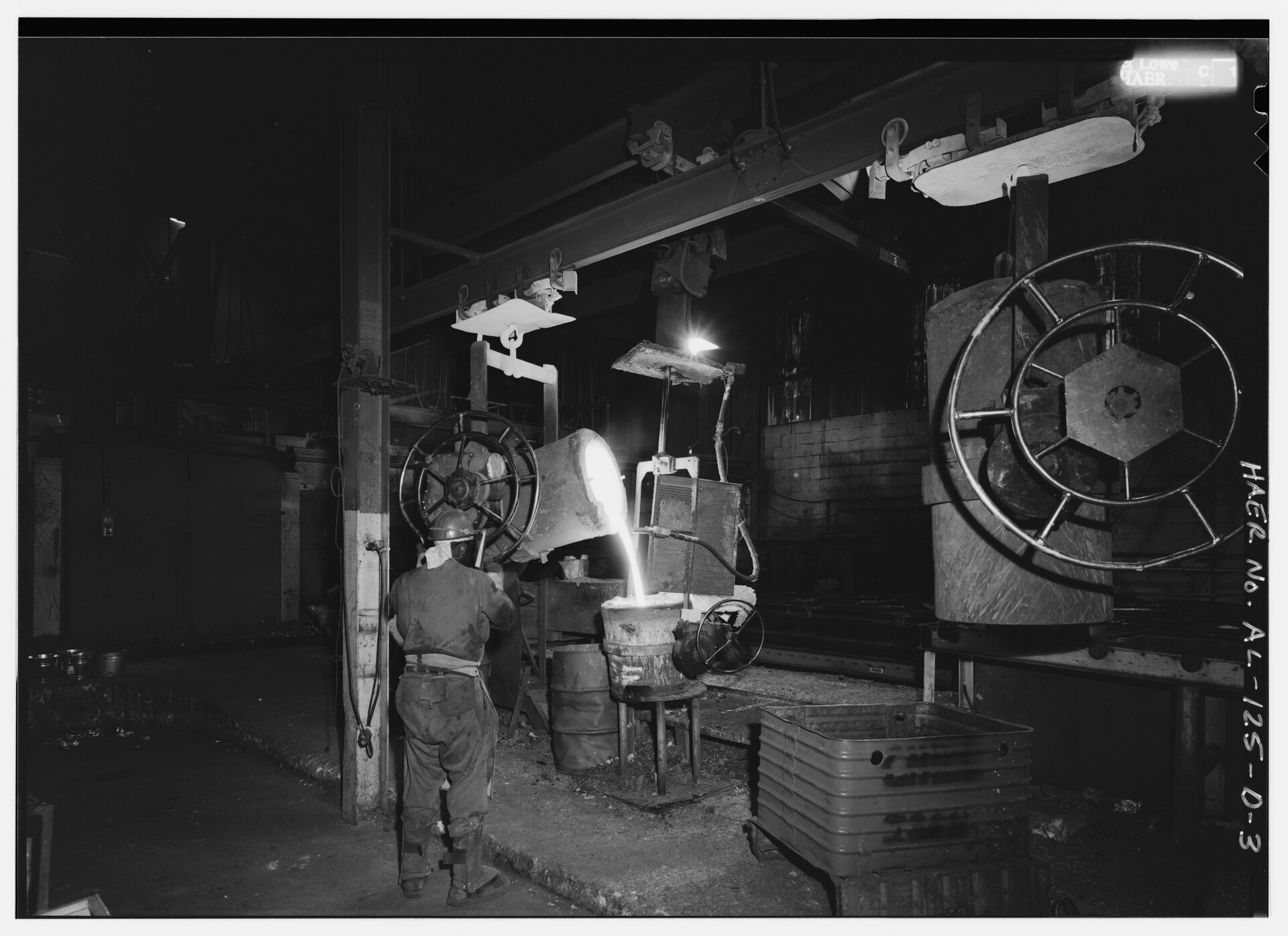 Workers pouring molten iron from a bull ladle into mobile ladles on a ductile iron casting line