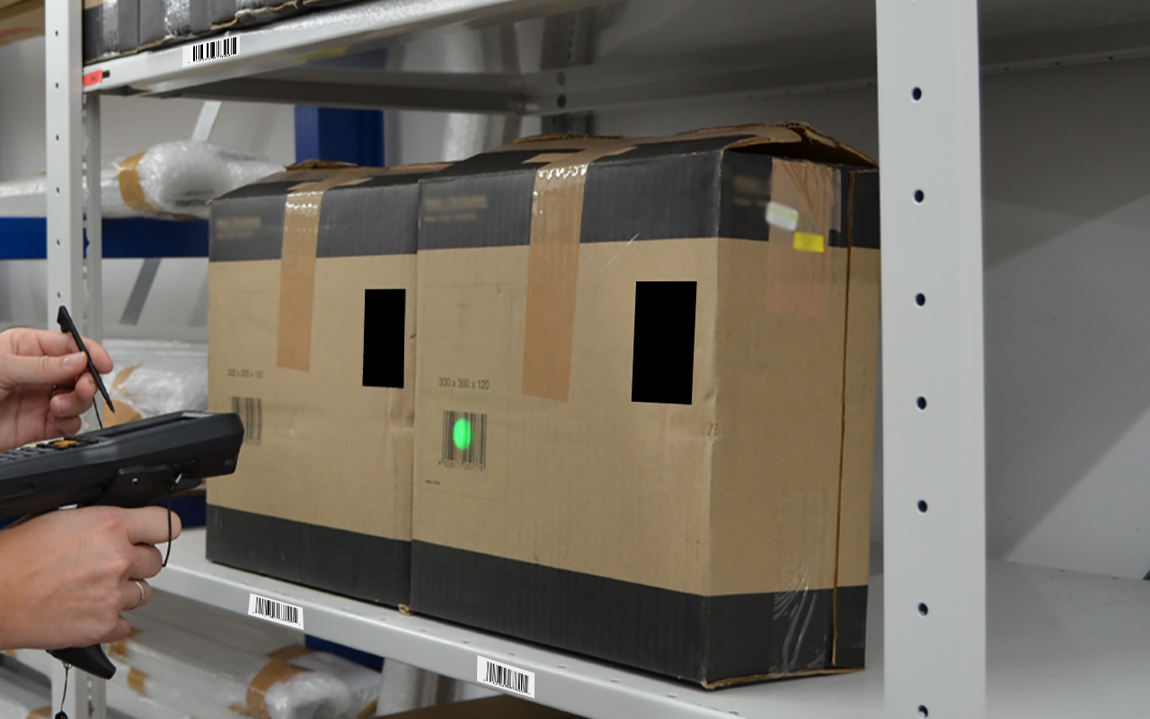Warehouse worker confirming a pick with a handheld barcode scanner in a rack aisle.
