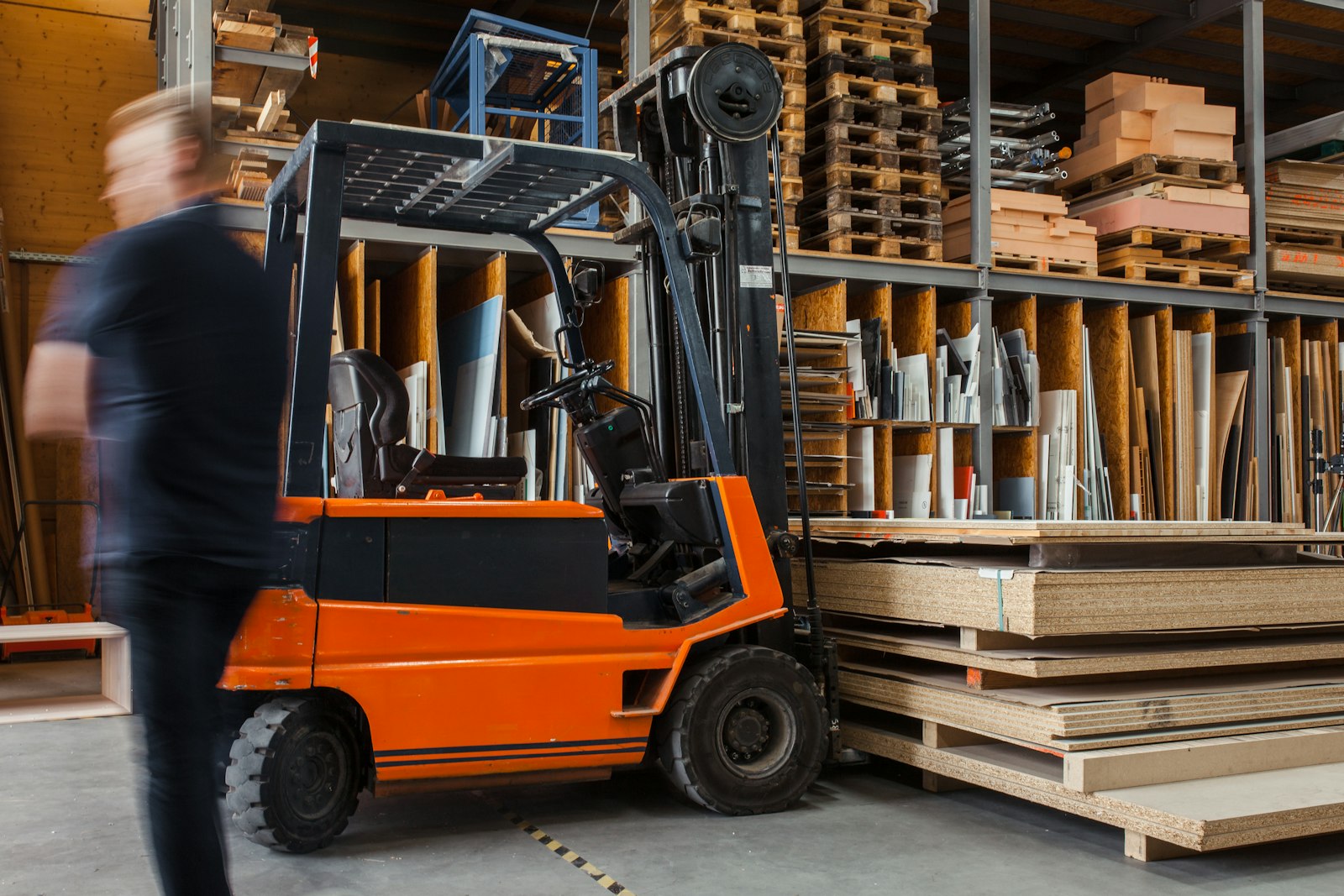 Worker with a forklift in a large carpentry warehouse. Photo: Pickawood / Unsplash.