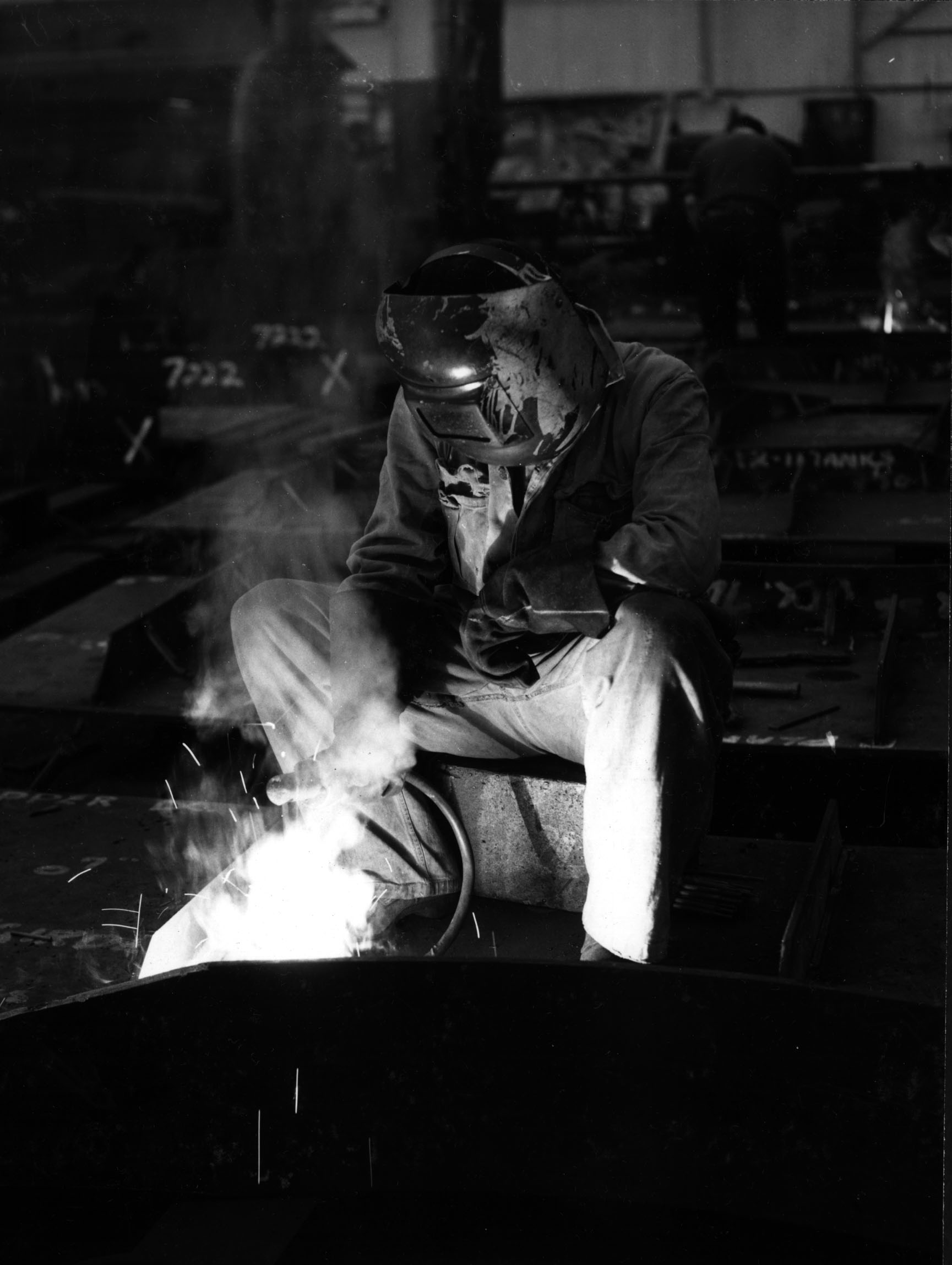 Black-and-white photo of a welder in a mask working inside the Hawthorn Leslie shipyard in Hebburn, 1960s.