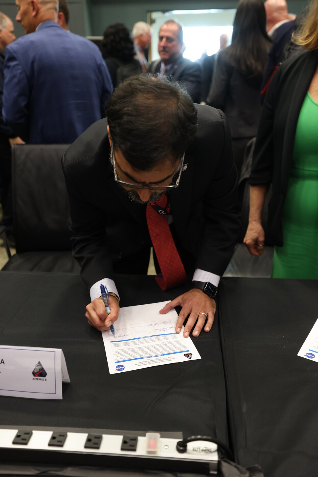 NASA Associate Administrator Amit Kshatriya signs the Artemis II flight readiness certification at a table at Kennedy Space Center. Photo: NASA, public domain, via Wikimedia Commons.