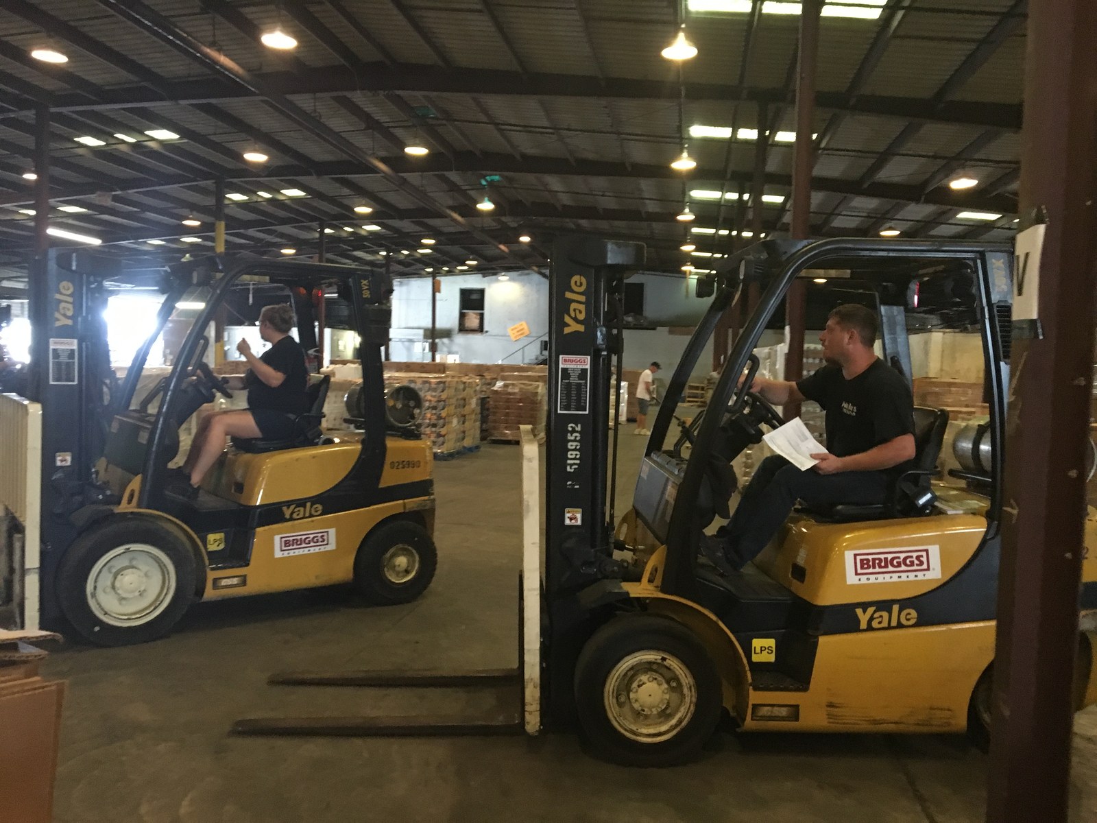 Warehouse forklifts among pallet racks—fulfillment side of manufacturing quotes where misspecified configs become costly warehouse and channel errors. Photo: TLSuda / Wikimedia Commons.