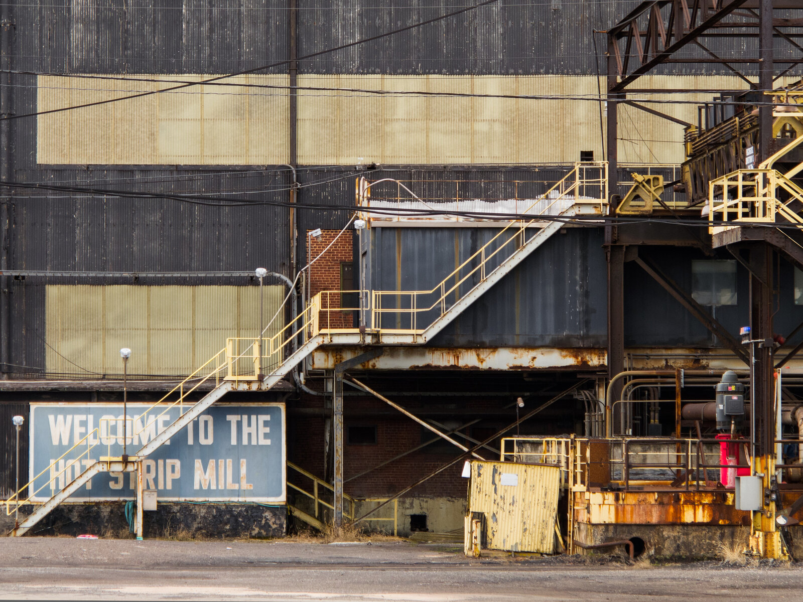 Entrance stairs and a Welcome to the Hot Strip Mill sign at a steel plant. Photo: Jason Knauer, CC BY 3.0, via Wikimedia Commons.