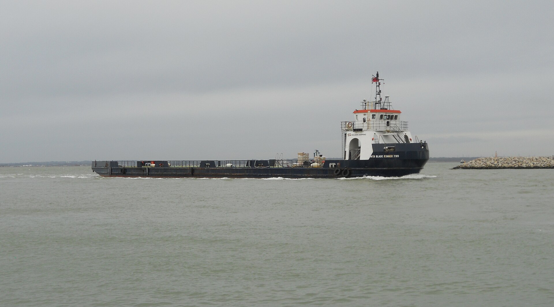 The wind turbine blade transport boat Blade Runner Two entering Cowes harbour, Isle of Wight, on its way to the Vestas blade factory. Photo: ITookSomePhotos, CC BY-SA 4.0, via Wikimedia Commons.