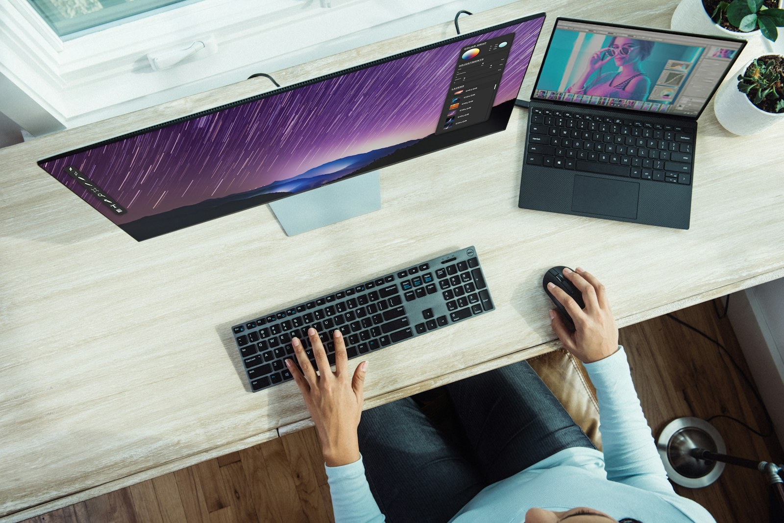 Engineer at a clean desk with a wide monitor and laptop reviewing technical work