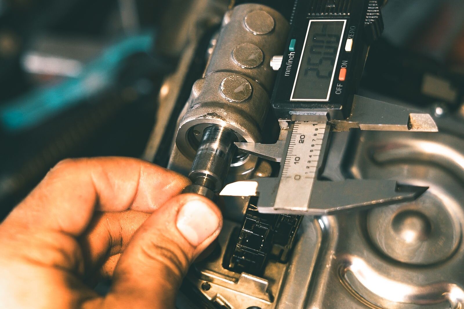 Technician measuring a machined component with a digital caliper