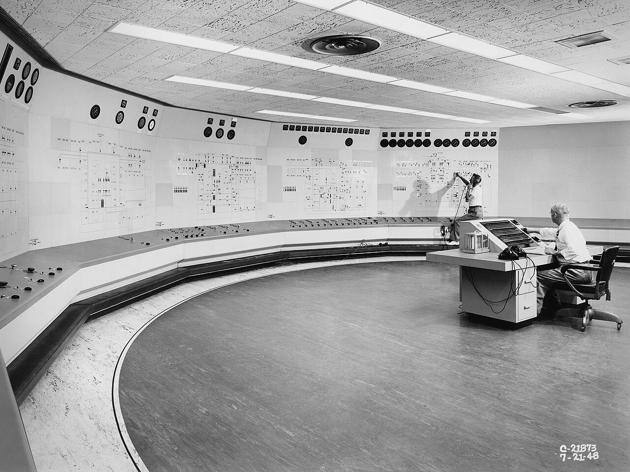 Operators at a long curved control panel in a 1948 NACA engine research control room.